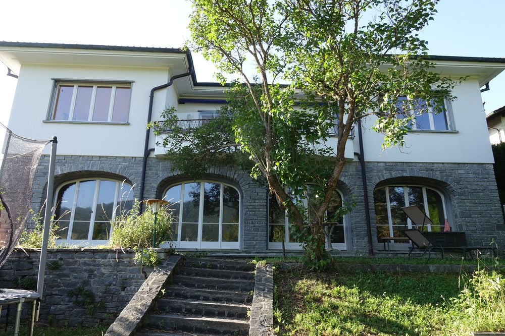 2 story villa, white walls, arched windows, stone base, tree, large balcony, steps, trampoline