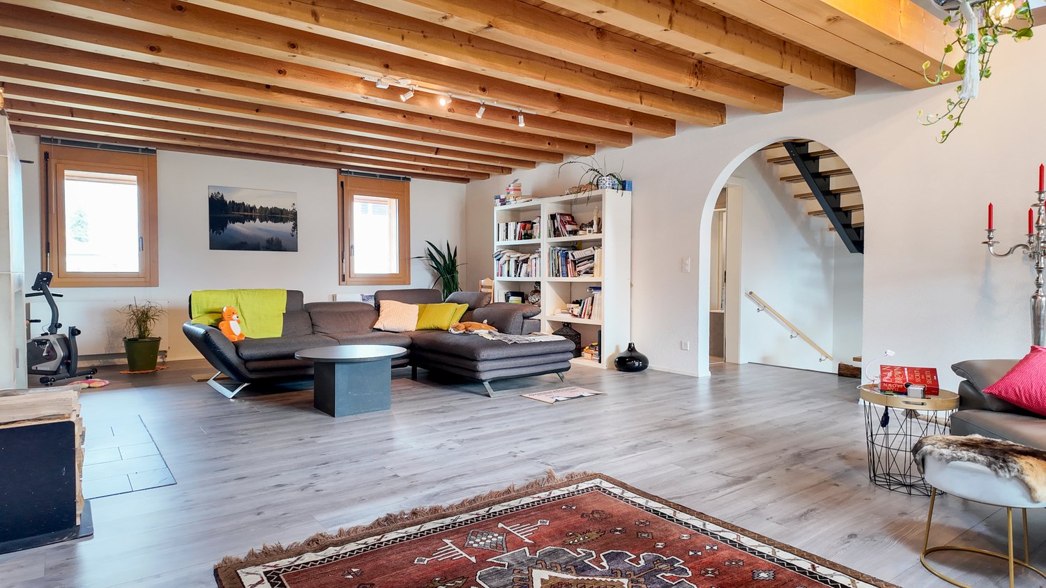 wood ceiling, large couch, book shelves, carpet, side table, windows