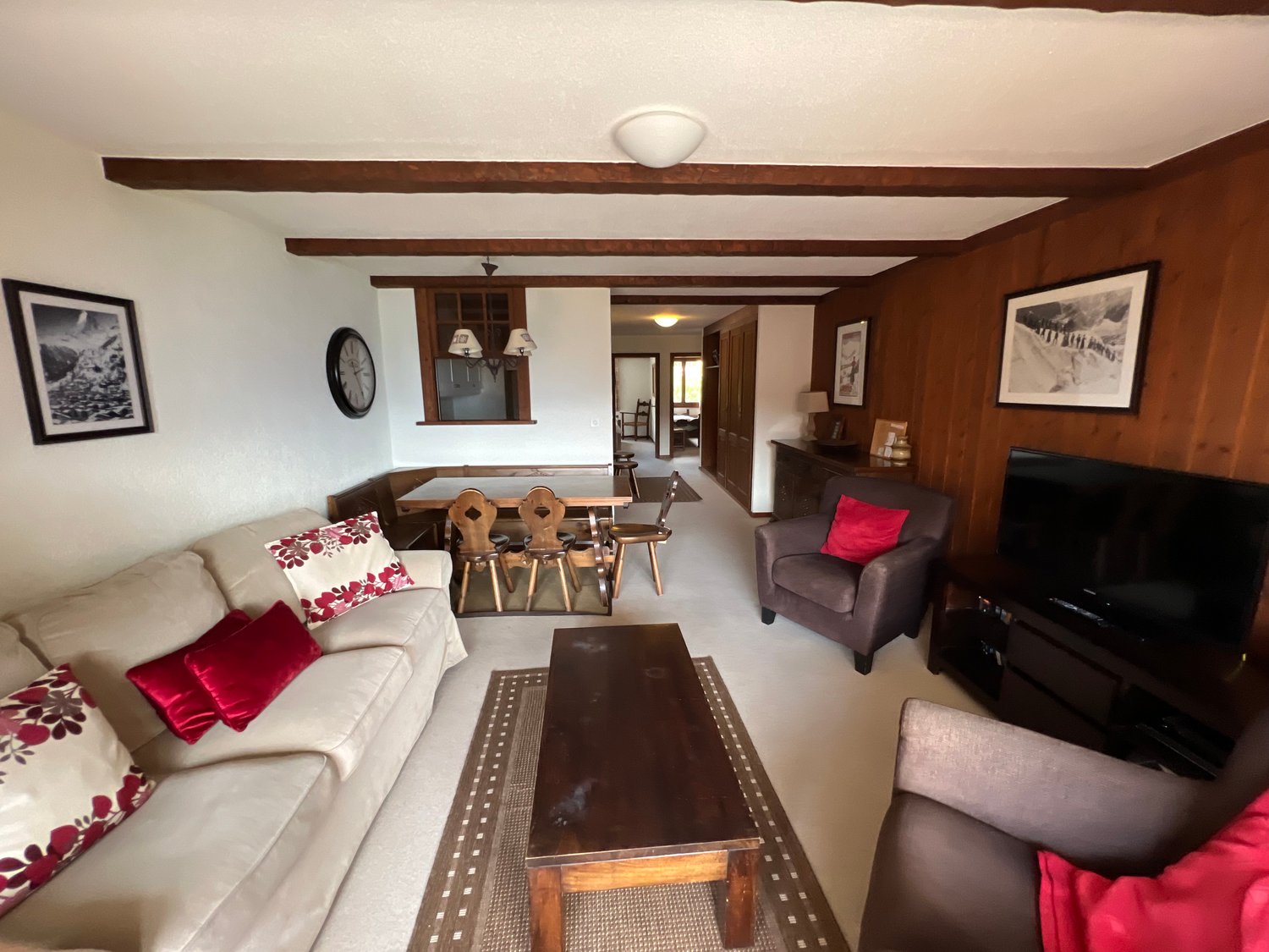 living room, sofa, coffee table, armchair, television, dining table and chairs, wooden wall, picture frames, carpet, wooden floor