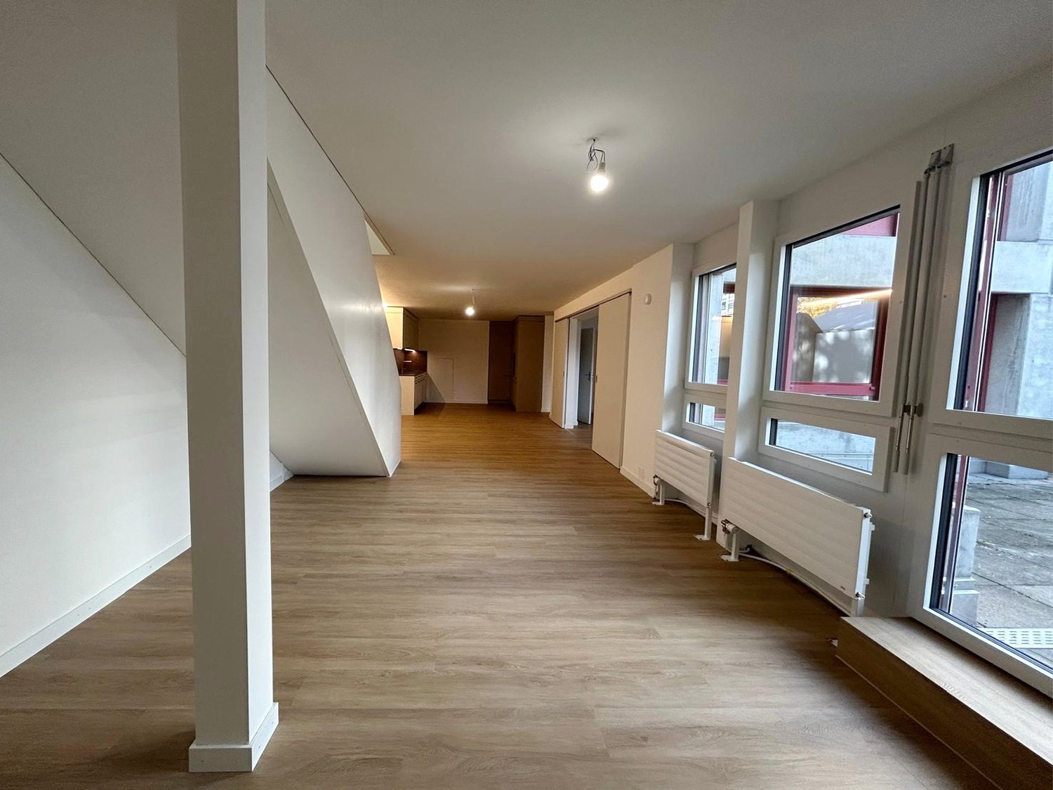 empty corridor, wooden floor, white walls, windows, light fixtures