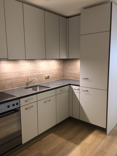 Modern kitchen, white cabinets, granite countertop, built-in oven, dishwasher, washing machine, stainless steel sink with faucet