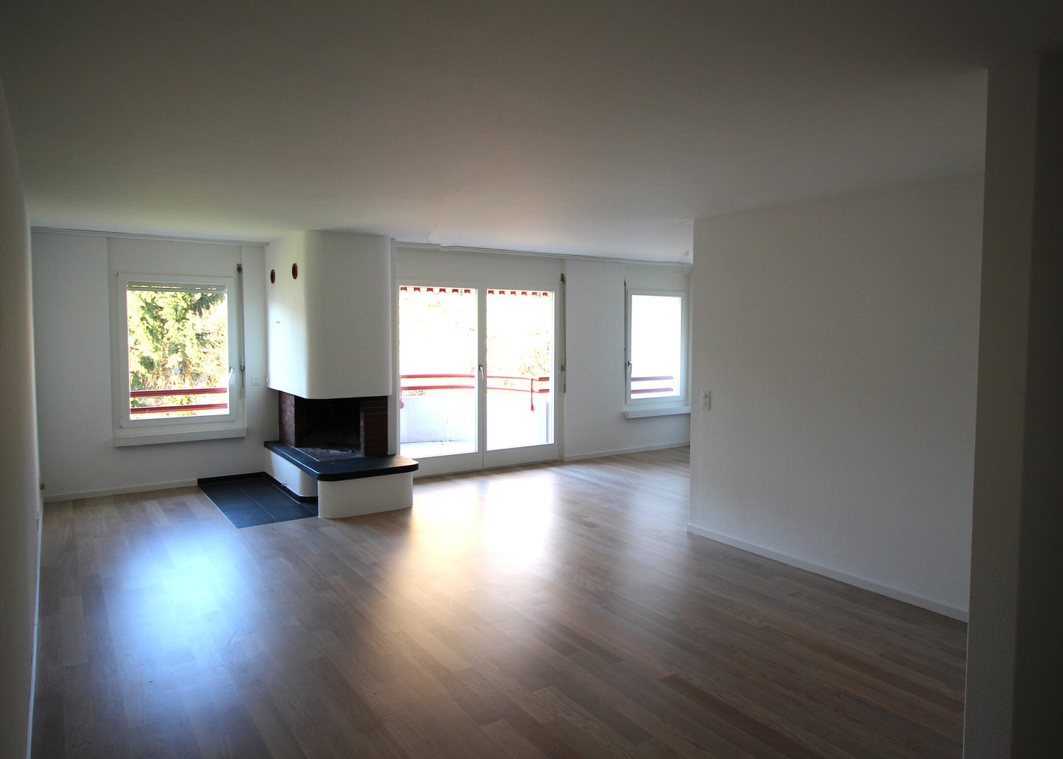 empty living room with fireplace, windows, and balcony