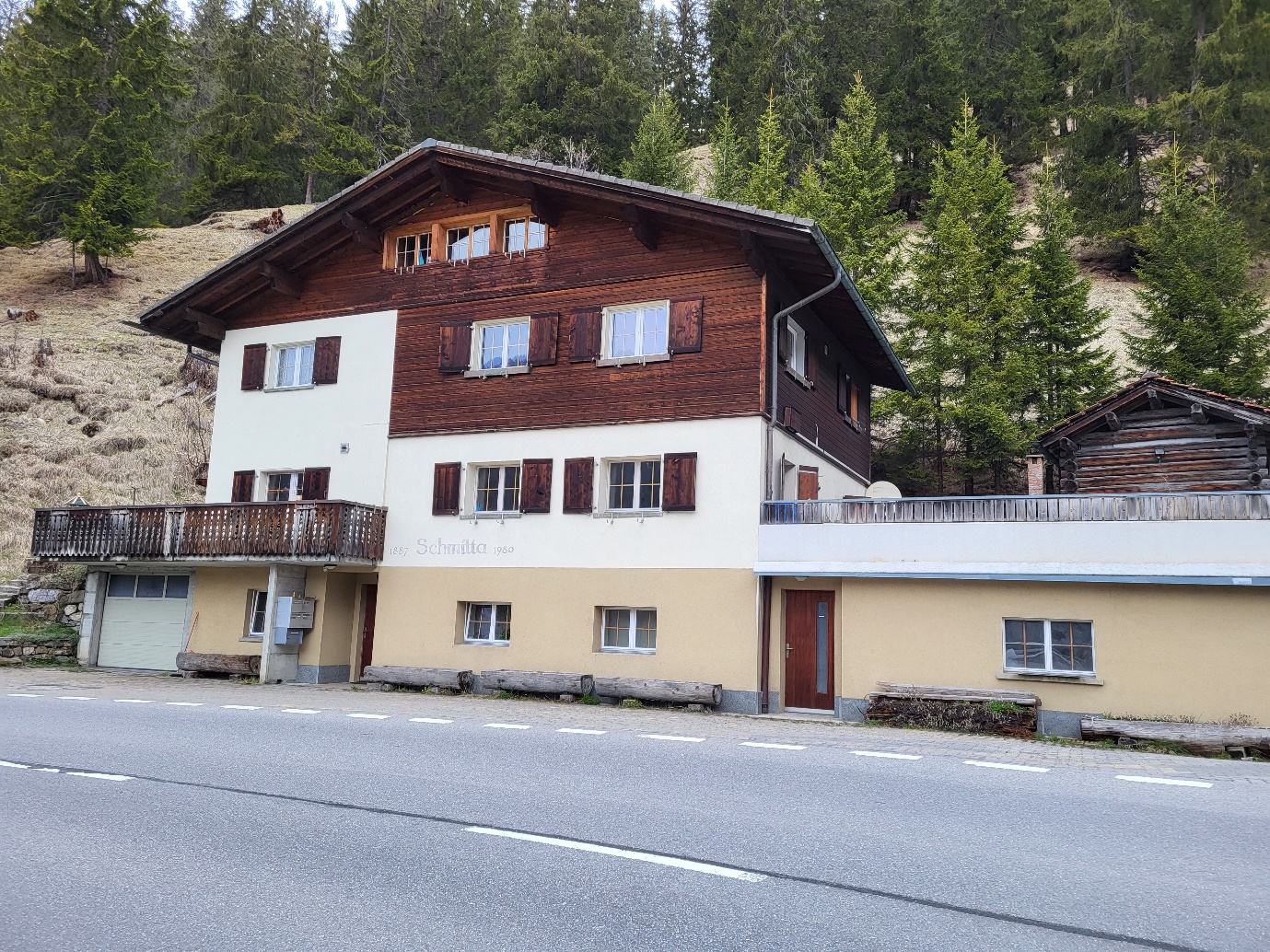 2 story house, brown wooden exterior, white walls, balcony, large windows, garage