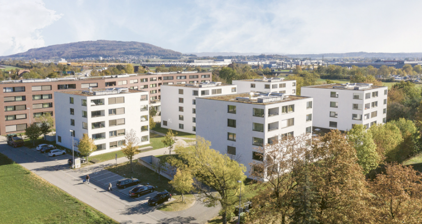 Multiple story apartment building, parking in front, green lawn, trees, green field, city in background, mountains