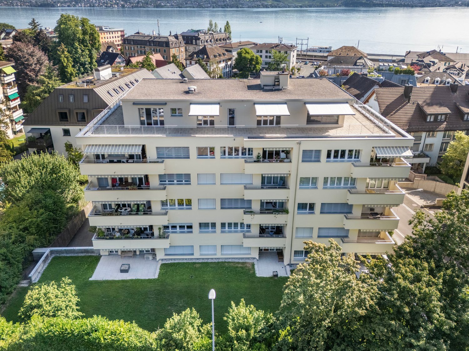 Apartment building with multiple balconies, green space in front, lake view