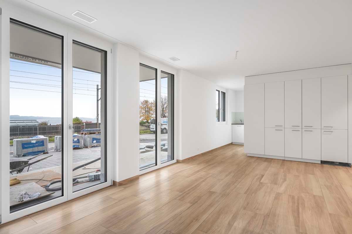 sliding glass doors, large windows, wooden floor, kitchen on the side, empty room