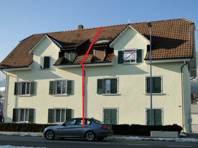 3-story building, beige paint, green shutters, red roof, car parked in front
