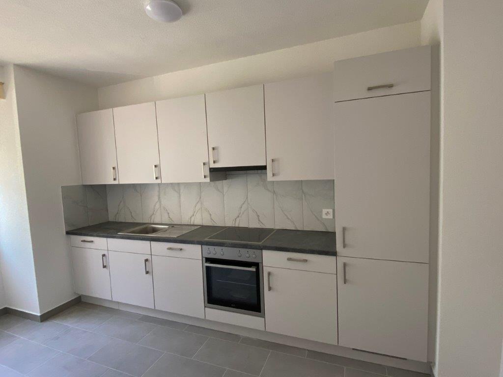 Modern kitchen with white cabinets, marble-patterned backsplash, built-in oven, and dishwasher
