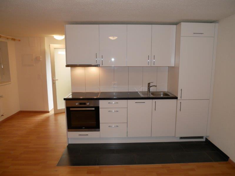 Modern kitchen with white cabinets, black countertops, built-in oven, and a dishwasher
