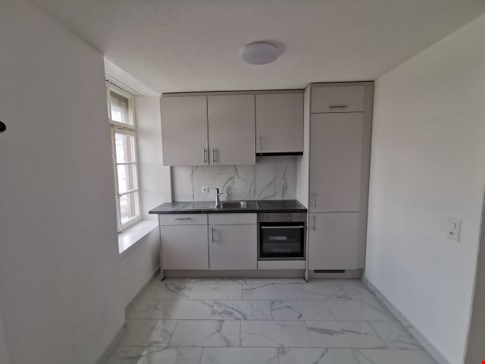 Spacious kitchen with white cabinets, stainless steel appliances including a dishwasher, and marble-like flooring.