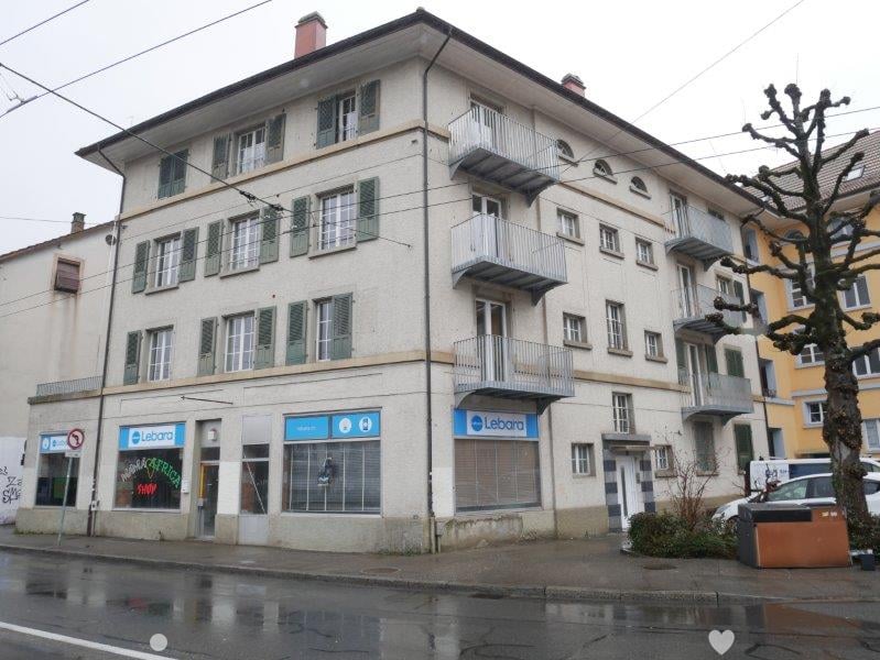 4 story building, multiple balconies, green shutters, commercial shops on the ground floor