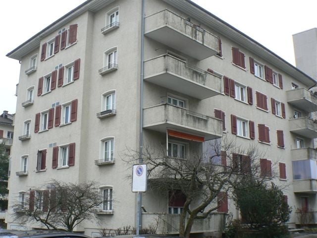 4 story apartment building, balconies, red shutters