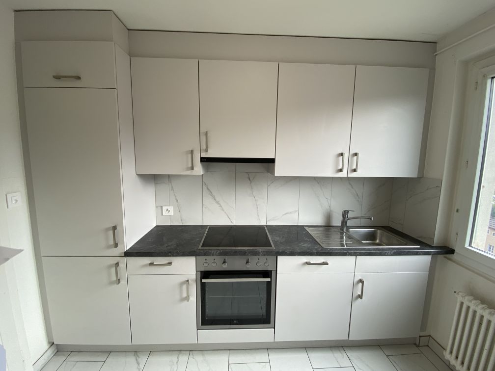 Modern kitchen, white cabinets, black granite countertops, integrated stove and oven, stainless steel sink, white floor