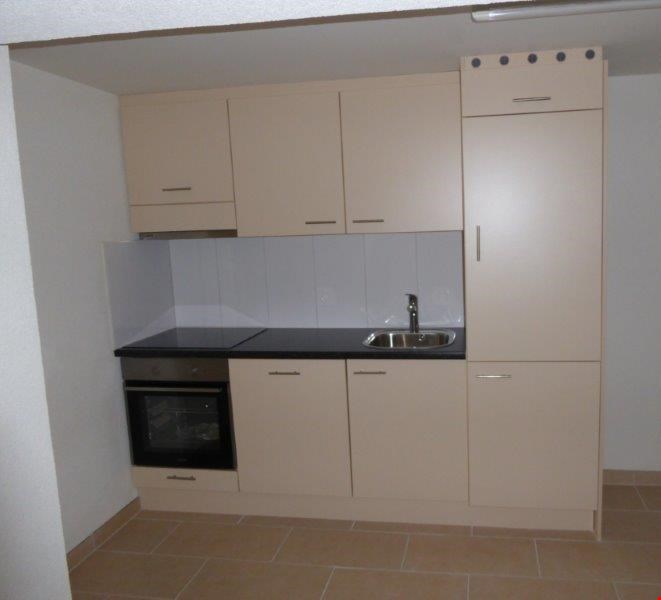 a kitchen with cream cabinets, tiled floor, sink, and oven