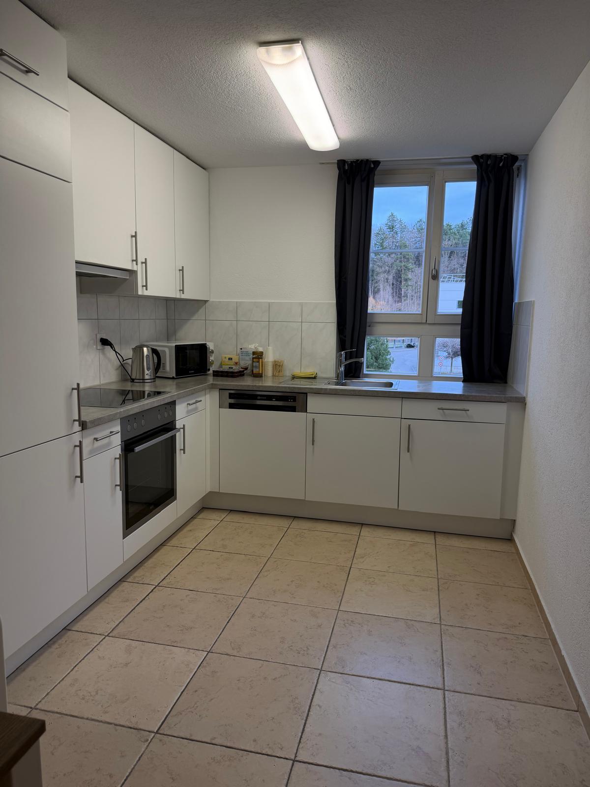 modern kitchen with tiled floor, integrated oven, dishwasher, window with curtain