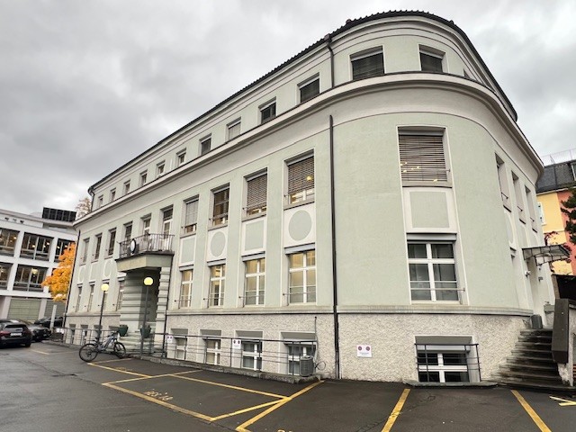 large white building, multiple windows, balcony, parking lot, street lights, stairs
