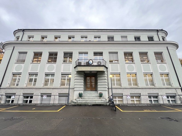 large white building, multiple windows, balcony, stairs, bicycle parked in front