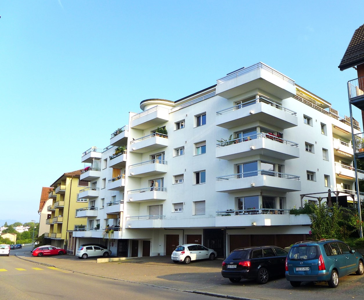 5 story white building, balconies, parking place, street