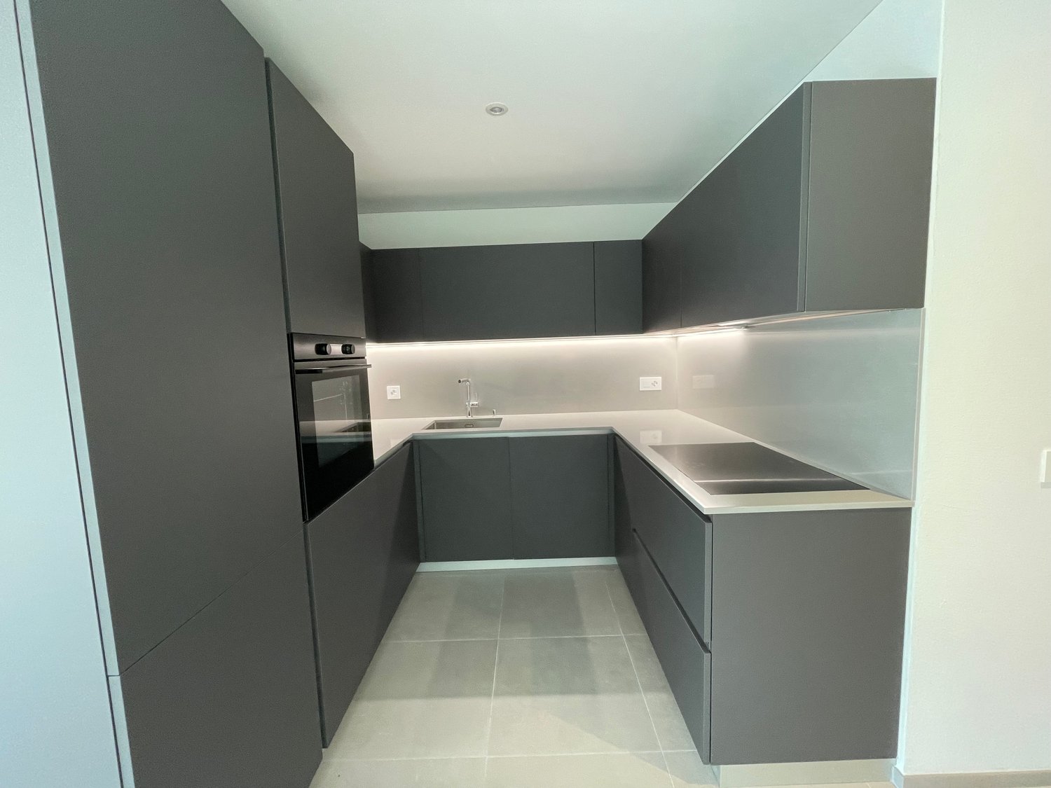 modern kitchen with black cabinetry, white countertops, integrated appliances, and a tiled floor