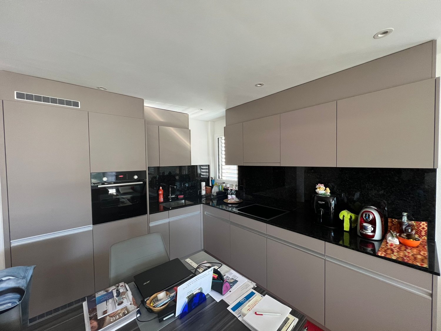 modern kitchen with large granite countertop, integrated appliances, gray cabinetry, black and silver accents, modern chandeliers, open concept with dining area