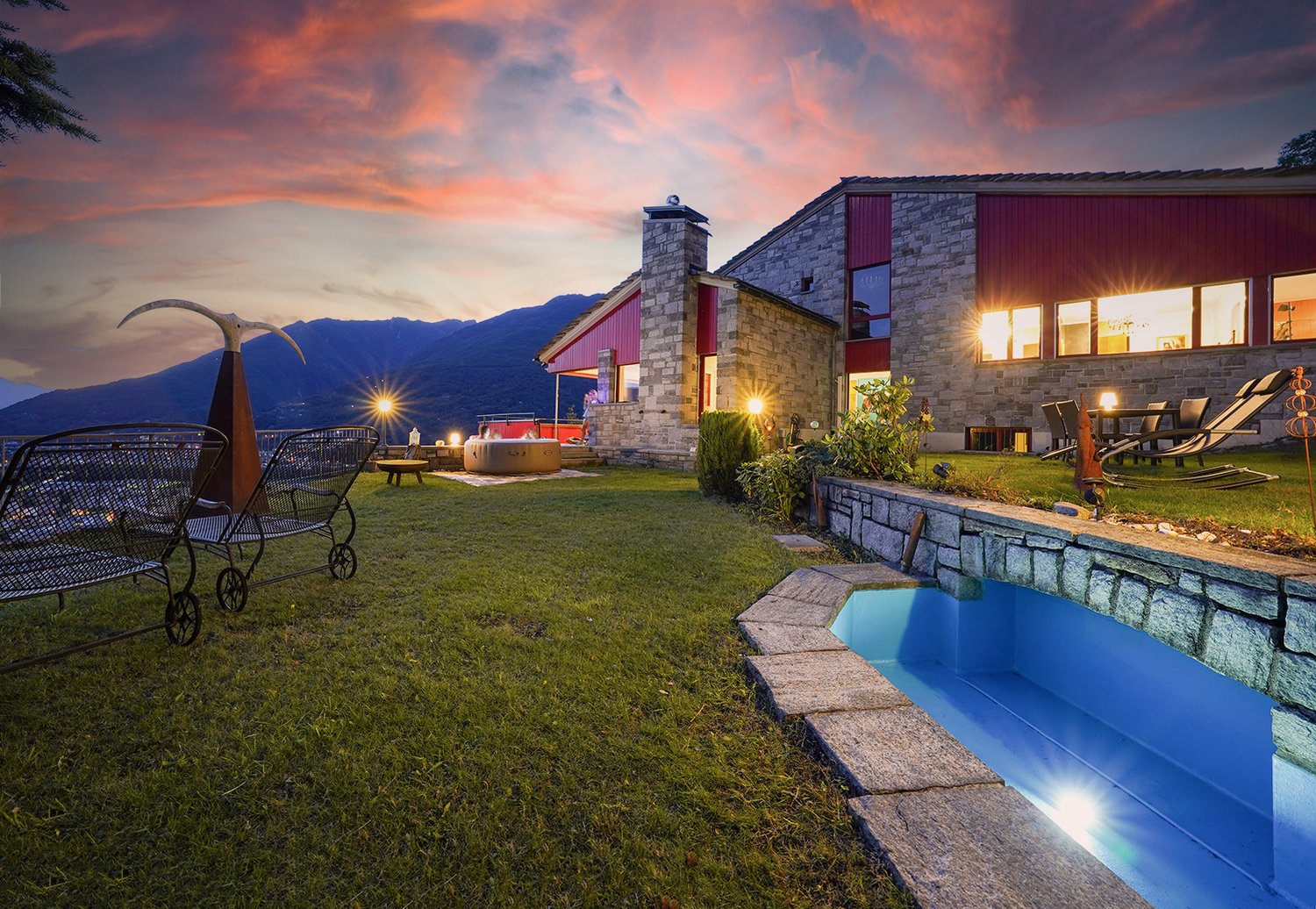 Modern house with outdoor pool, garden, mountains in background, evening lights