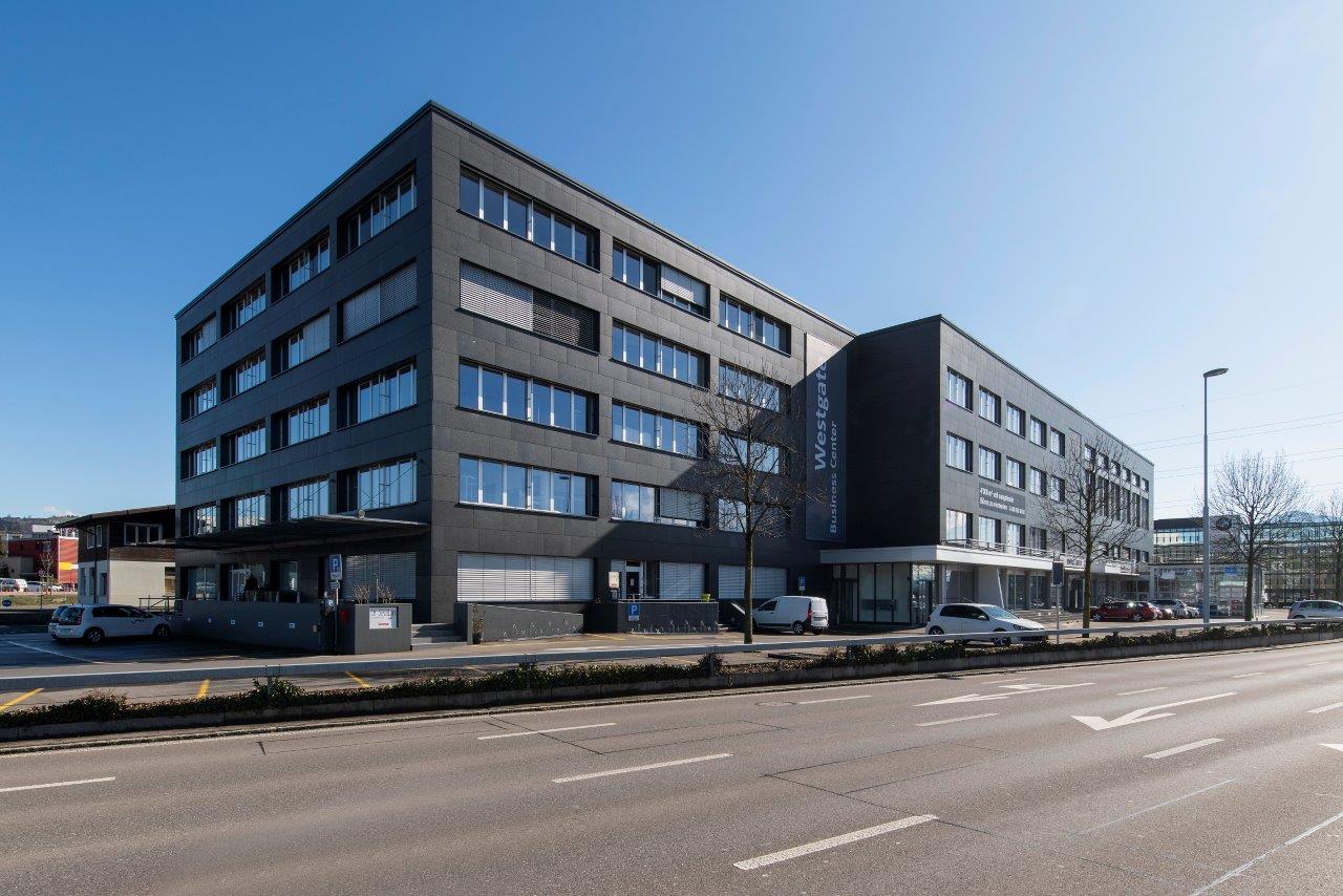 modern office building with multiple windows, concrete facade, ground floor entrance, parking area