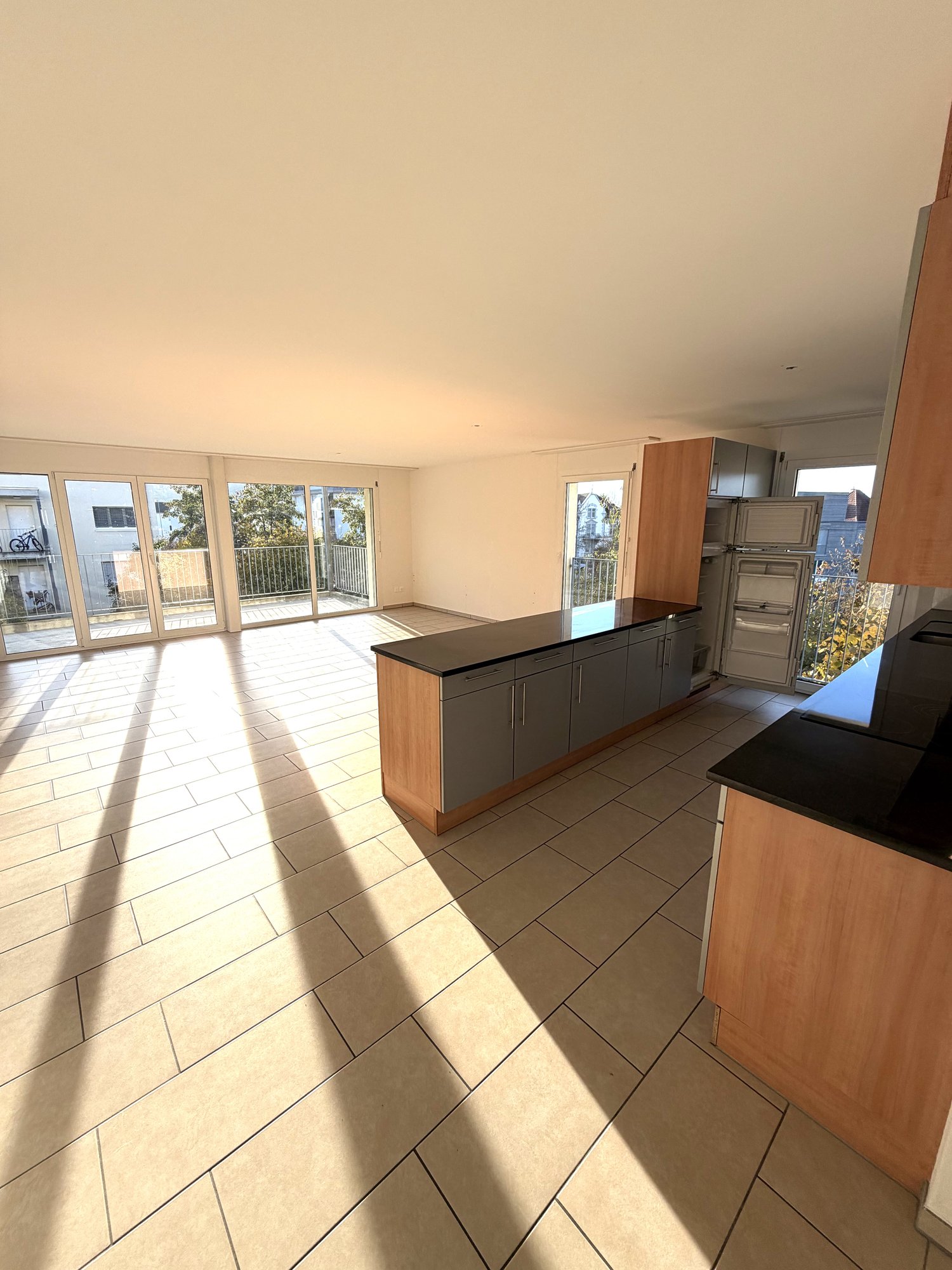 Spacious kitchen with wooden countertops, cabinets, and appliances. Large sliding glass doors leading to a balcony with a view.