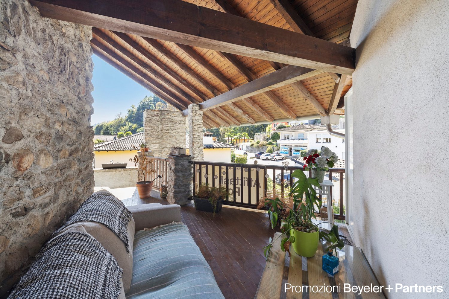 wooden deck with railings, stone wall, potted plants, outdoor furniture, view of the surroundings