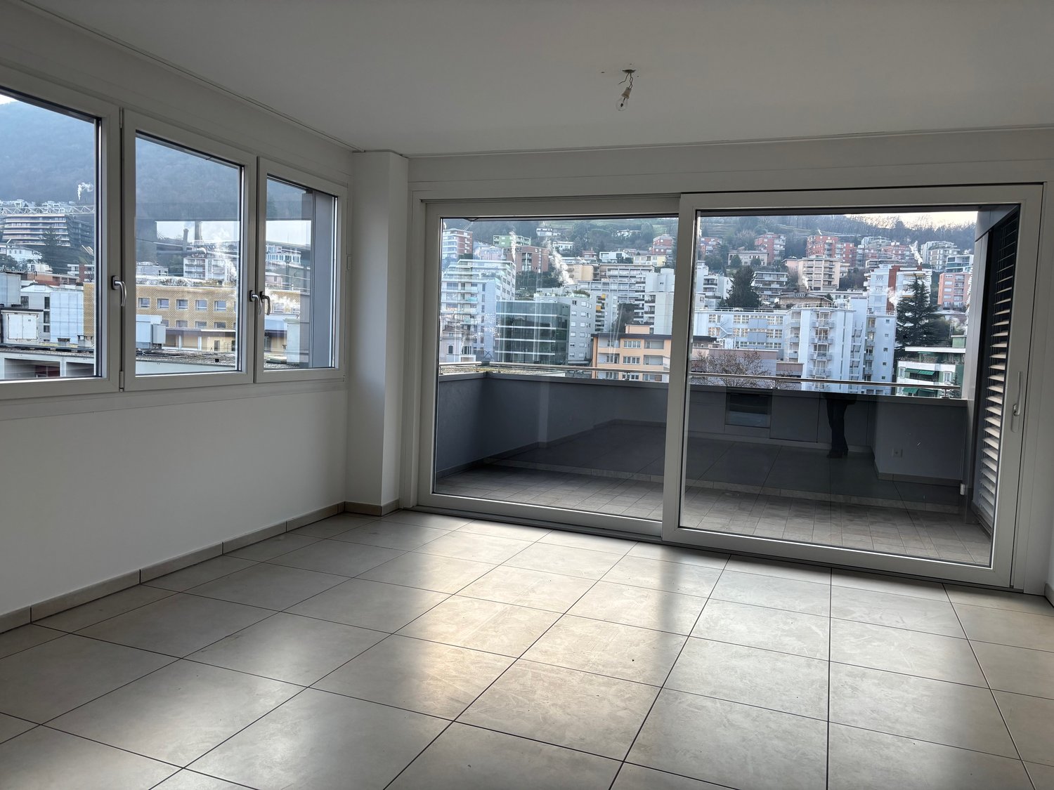 empty room, sliding glass door to balcony, tile flooring, windows, balcony with view