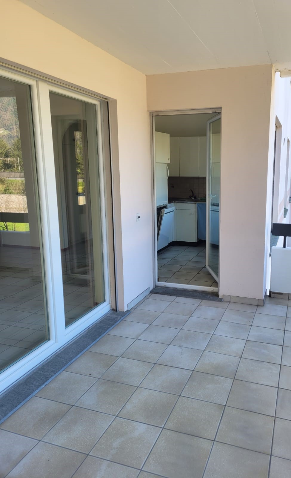empty balcony with large glass sliding doors, tile flooring, leading to kitchen