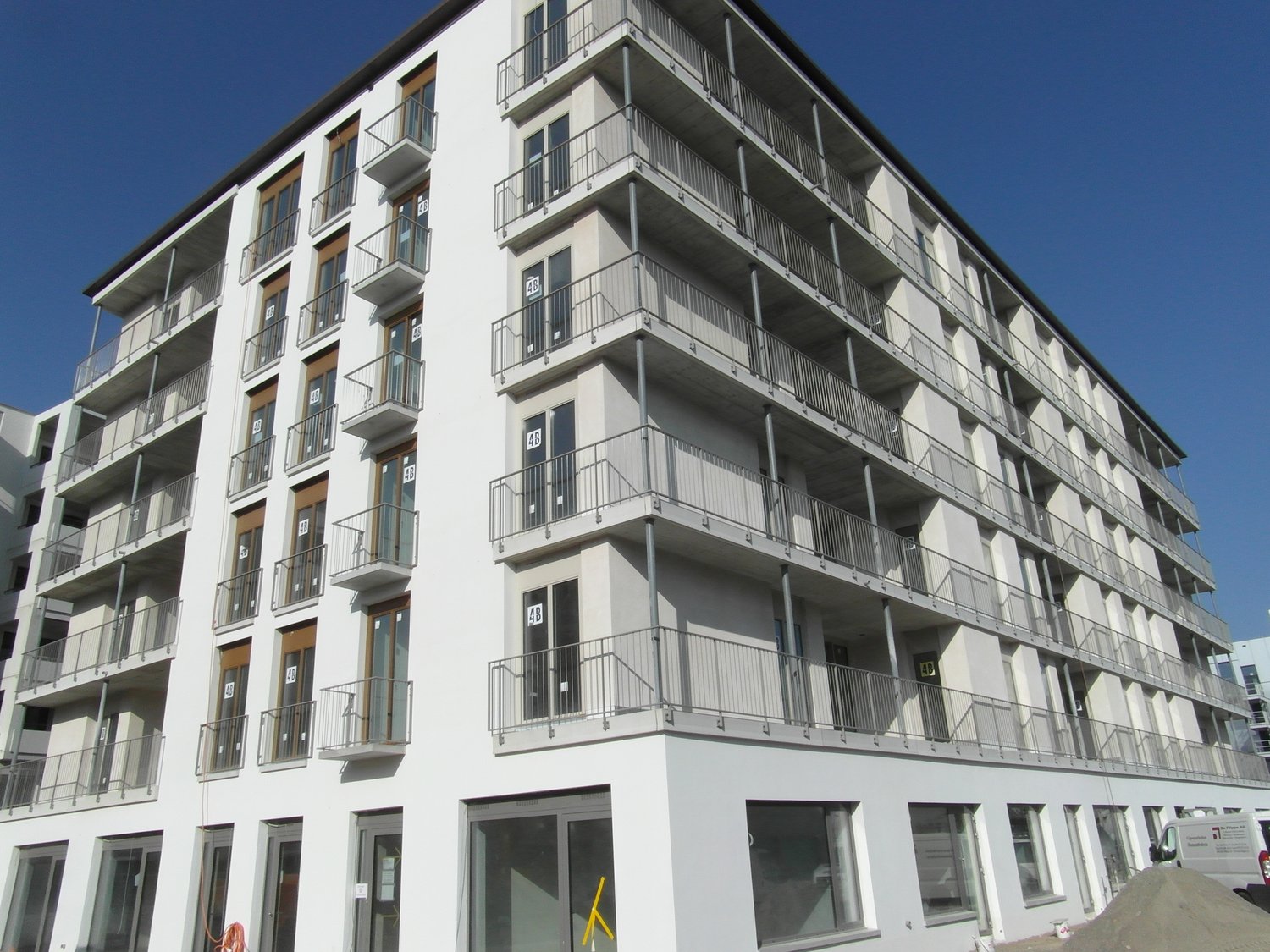 Modern apartment building, multiple floors, balconies, large windows, white exterior