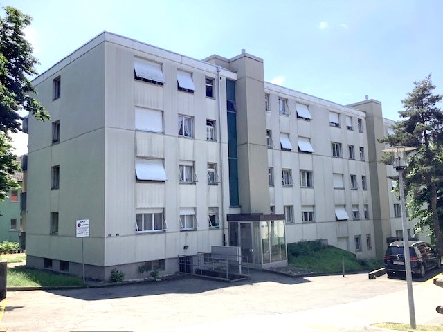 multi family residential building, white exterior, many windows, paved parking lot