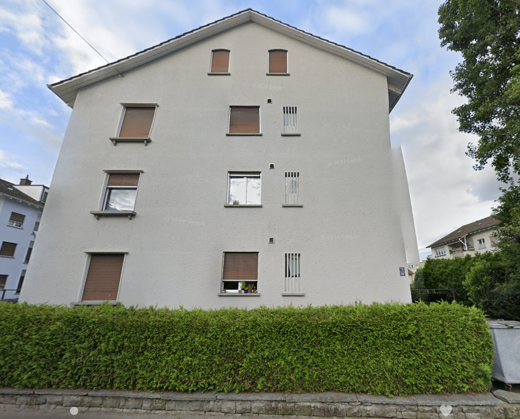 3 story apartment building, white exterior, wooden shutters, large windows, small garden in front