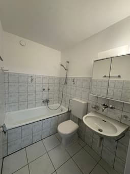 Bathroom: white tiles, bathtub, toilet, sink, mirror