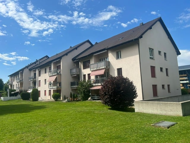 Three story house, white exterior, red windows, balconies, brown roof, front garden
