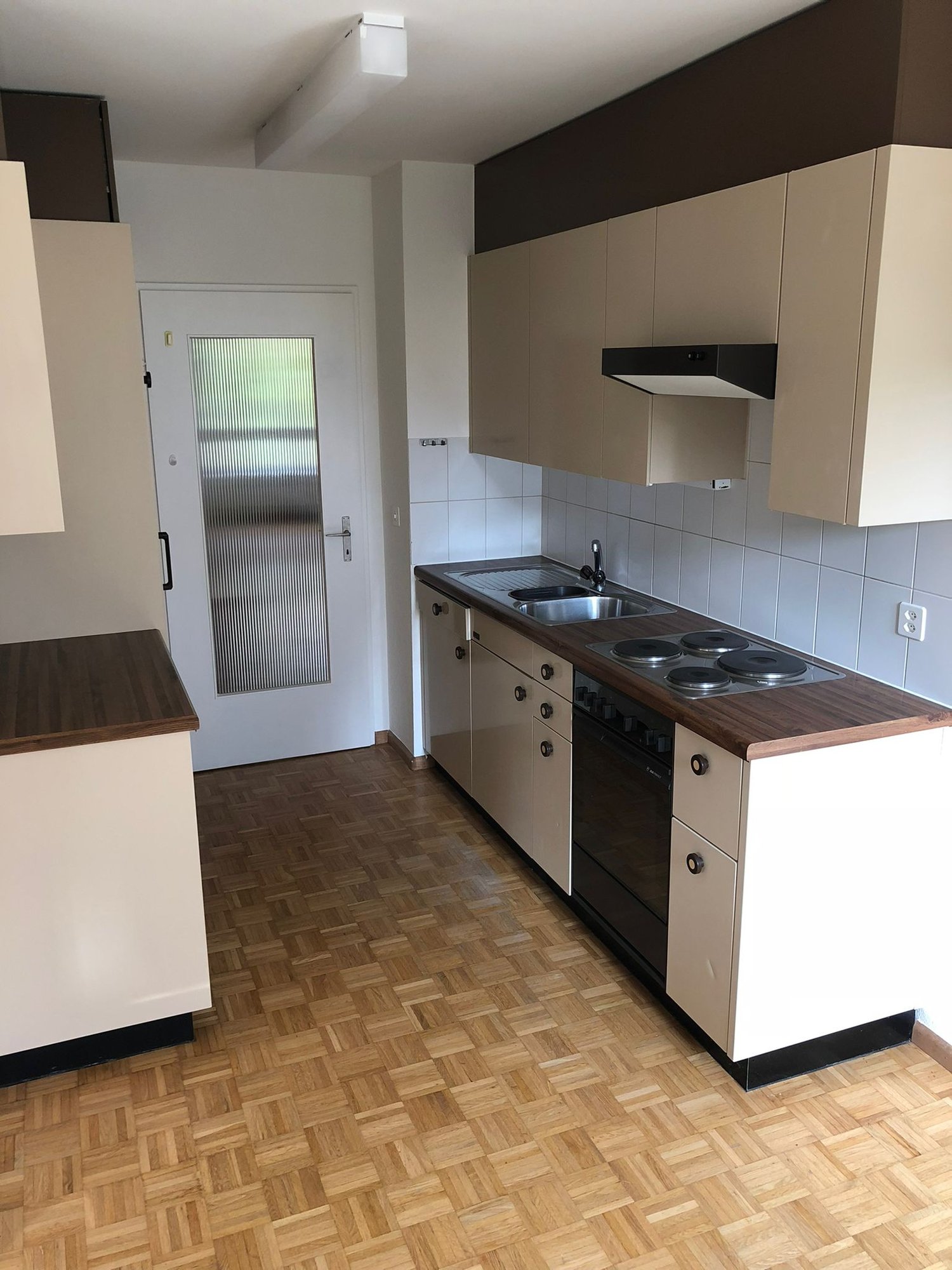 small kitchen, wooden floor, white cabinets, integrated appliances, sink, stove