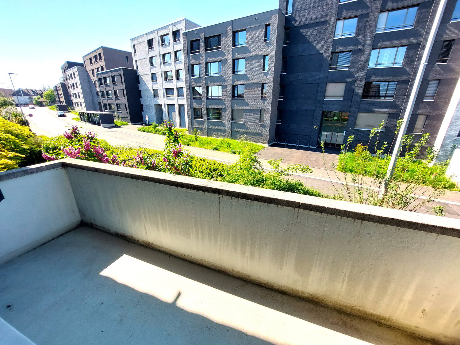 A modern apartment balcony with concrete railings and urban view