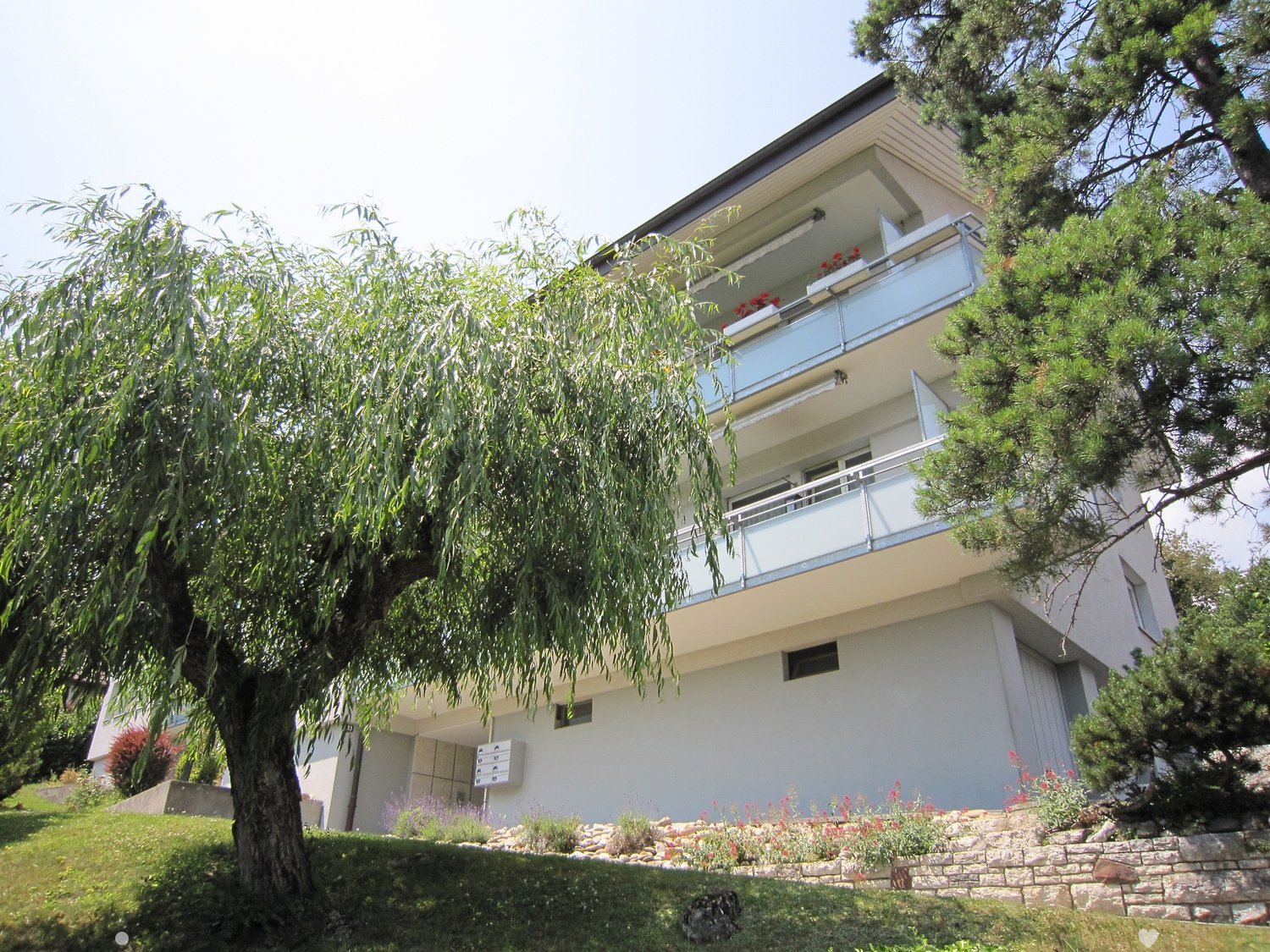 3 story white house, balcony, tree in front, garden, stone wall