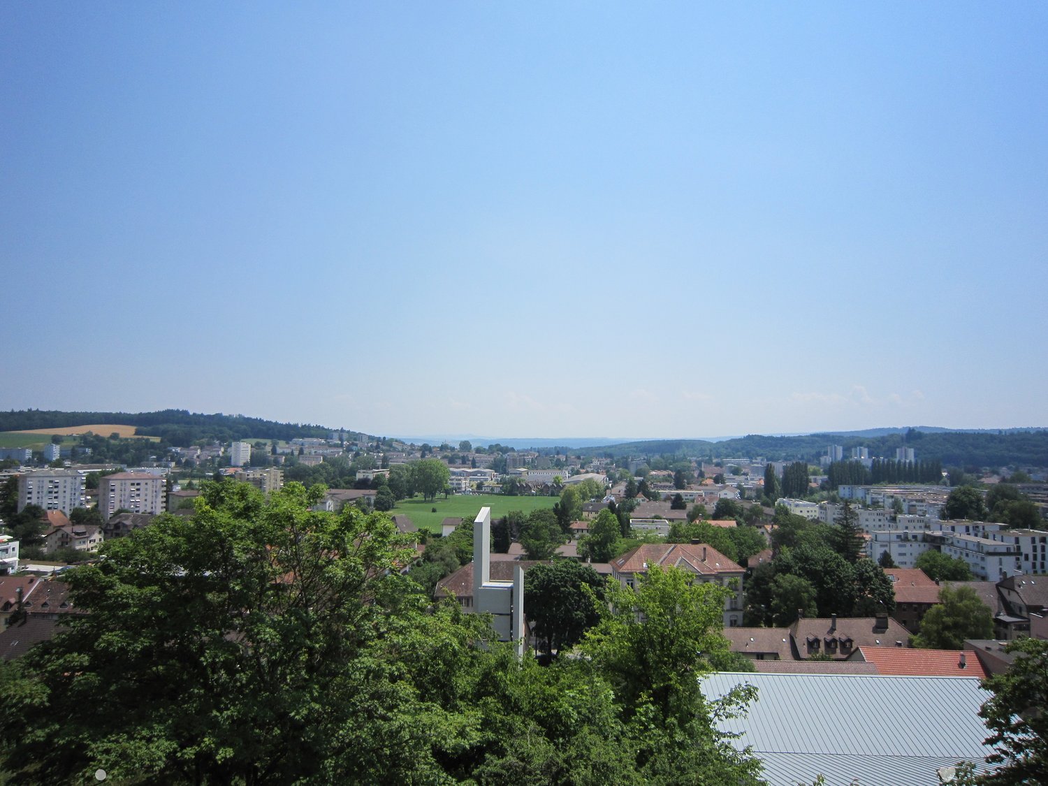 Cityscape with multiple buildings, trees, and a clear blue sky