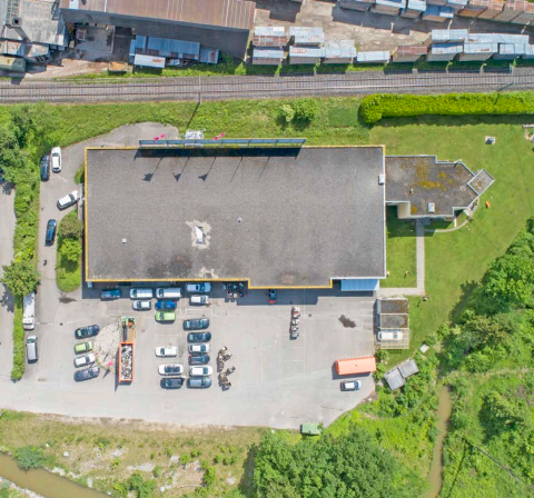 Large building with an attached parking lot and vehicles parked in it.
