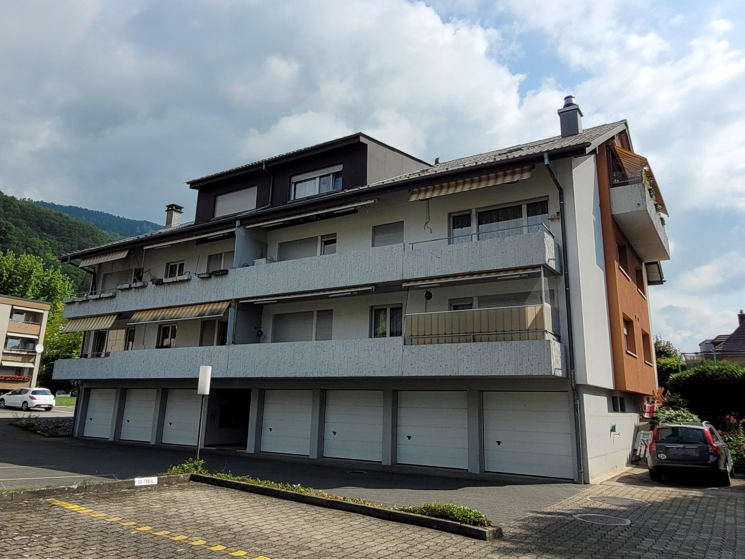 Multi-storey house, white exterior, brown accent, balconies, garages