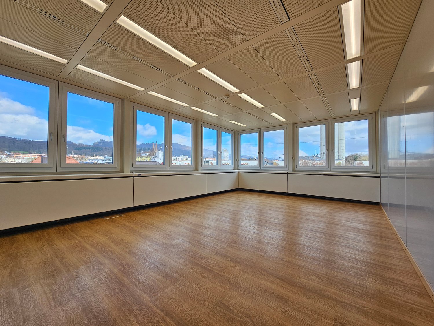 large room, wooden floor, large windows, bright