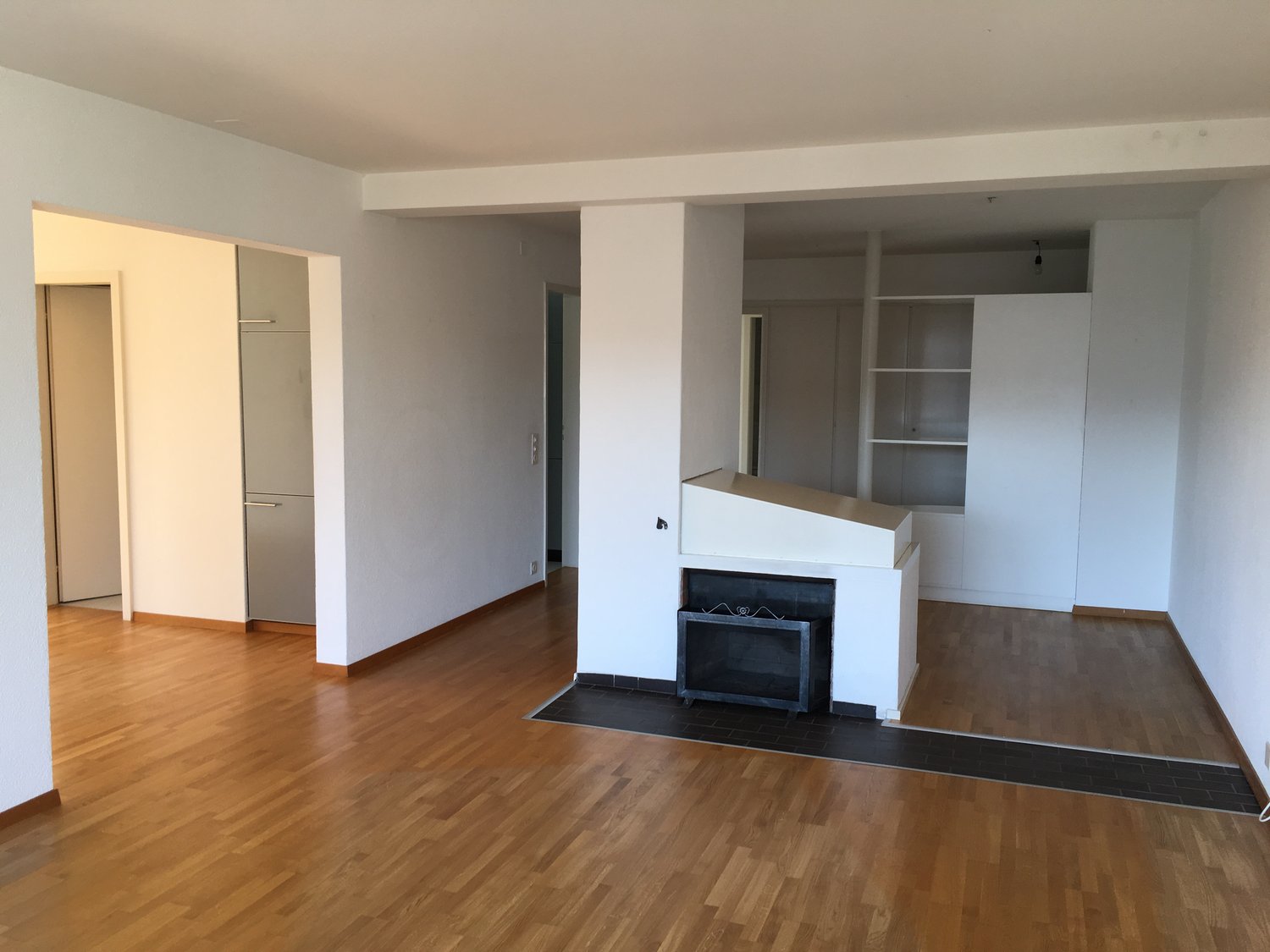 empty room, wood floors, white walls, white fireplace in a corner