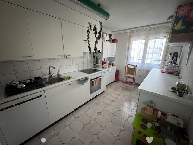 Spacious kitchen with white cabinets, tiled floor, gas stove, and a dishwasher