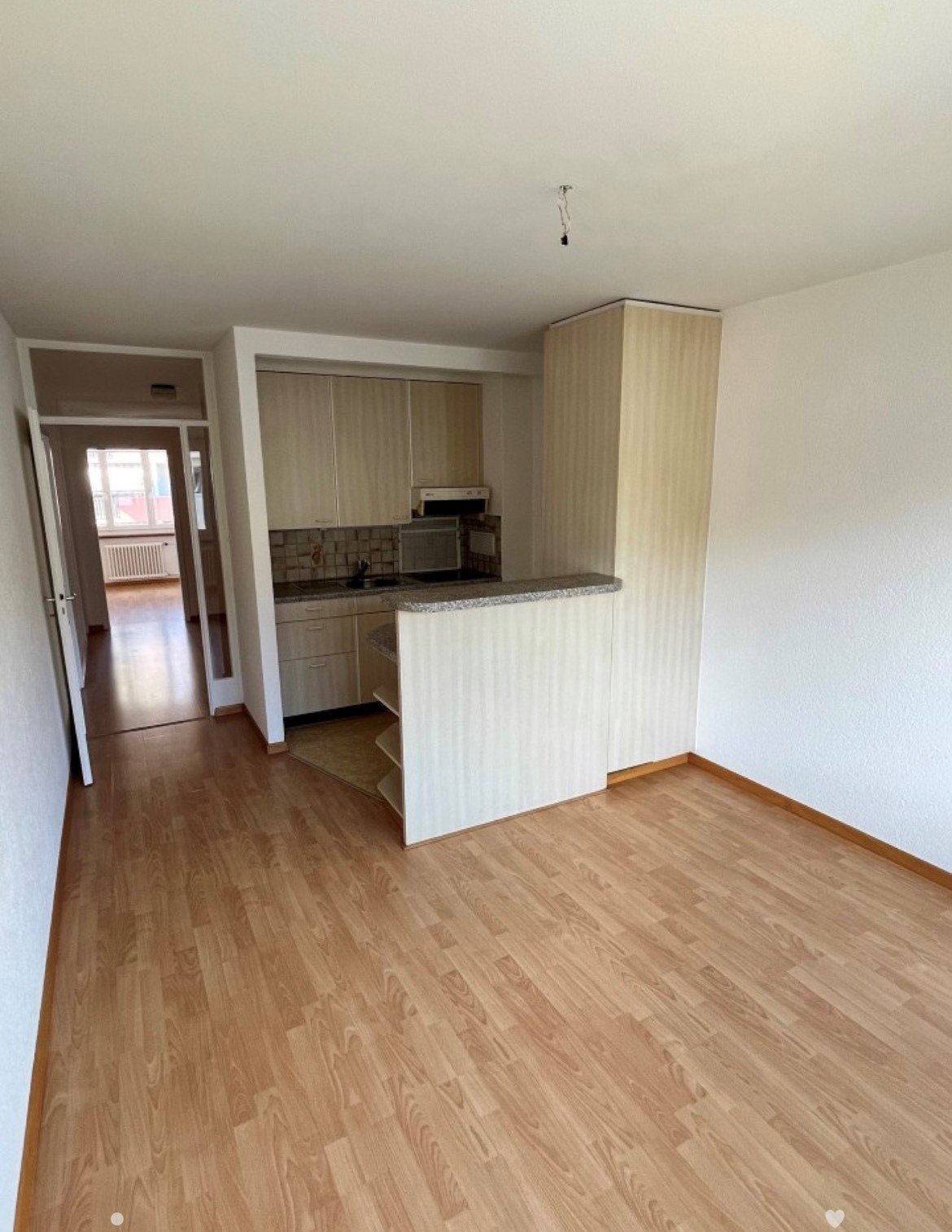 Open kitchen, wooden floor, kitchen appliances, countertop, cabinets, white walls