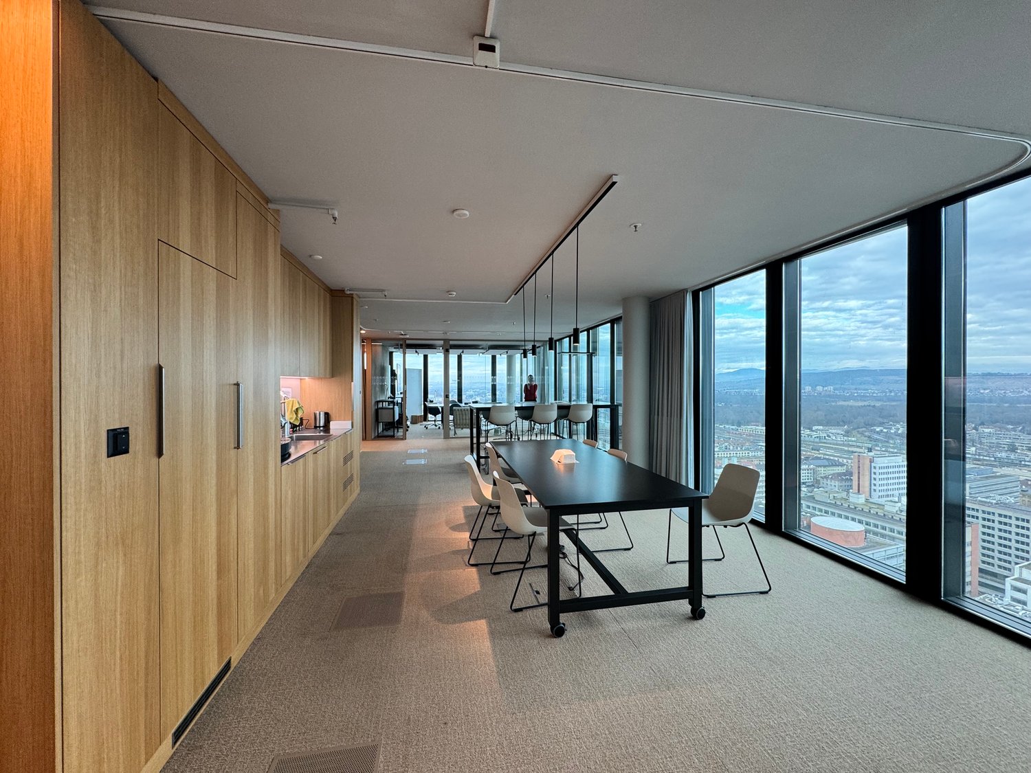 modern office space, with glass walls, white desks, beige carpet, wooden wall paneling, long conference table, office chairs, clear view
