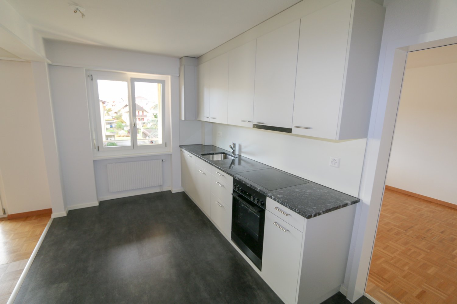 modern white cabinets, granite countertop, stainless steel appliances, built-in oven and dishwasher, sink with faucet, window with view of the outside