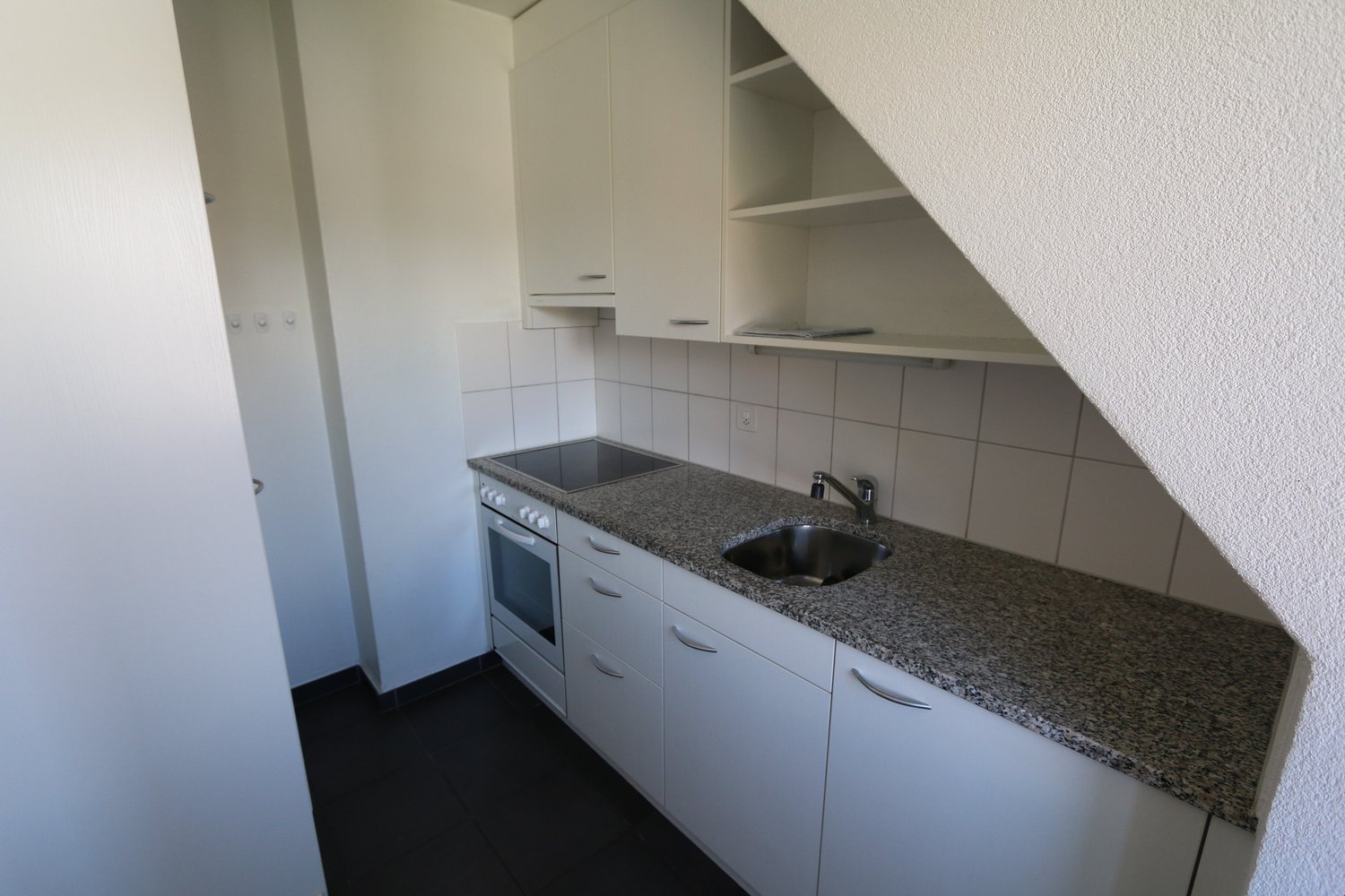 White cupboards, granite counter, sink, faucet, stove, oven, tiled wall, dishwasher