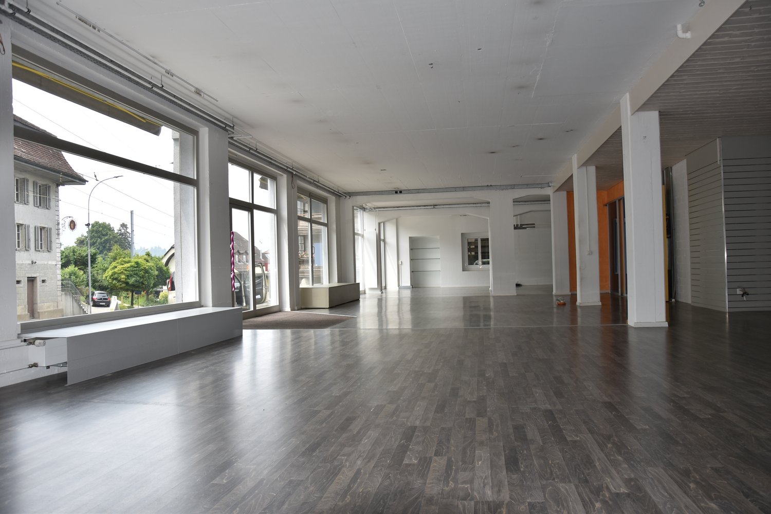 Large open space, hardwood floors, large windows, bench, and industrial-style interior design.