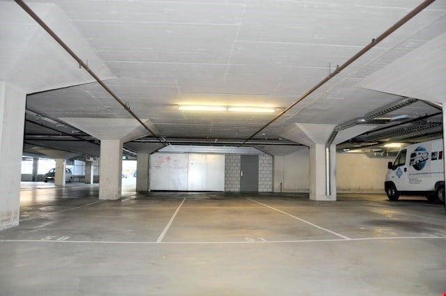 Underground parking lot with white concrete floor, white walls, concrete columns, bright lighting